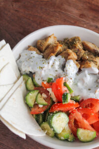 Low Carb Greek Chicken Bowls packed with everyone's favorite greek flavors!  Delicious in a bowl with cucumber and tomato salad, onions, homemade tzatziki, and feta cheese.
