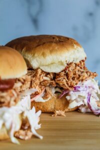 When warm weather comes around, I start putting easy, refreshing meals in the rotation, including these Low Carb Pulled BBQ Chicken Sandwiches.  Pulled chicken with keto barbecue sauce, and keto coleslaw on a low carb bun - these are easy to put together and great during hot weather.