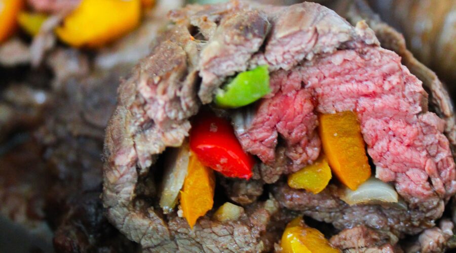 Flank Steak marinated then stuffed with bell peppers and onions.  Marinate, roll, and bake, then finish in the oven for a delicious dinner!