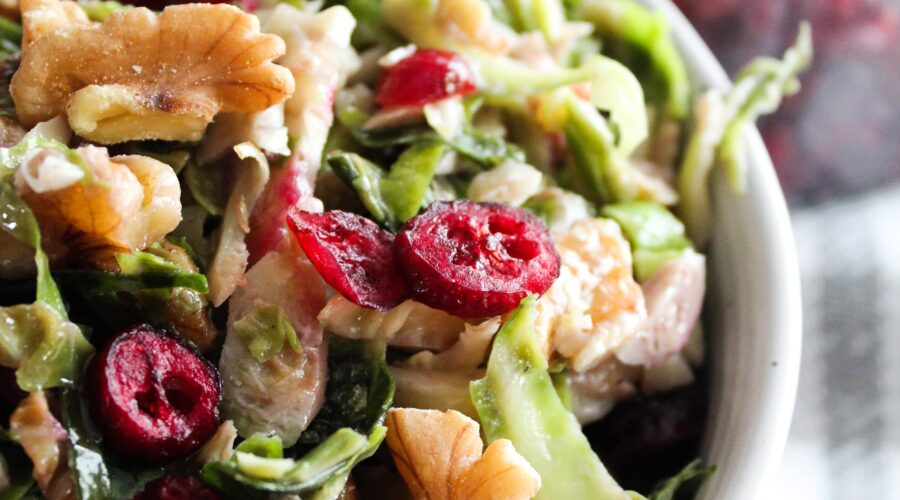 The most delicious Keto Shaved Brussel Sprout Salad made with raw brussels sprouts, dried cranberries, walnuts, and goat cheese in a sweet and tangy vinaigrette.