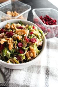 The most delicious Keto Shaved Brussel Sprout Salad made with raw brussels sprouts, dried cranberries, walnuts, and goat cheese in a sweet and tangy vinaigrette.