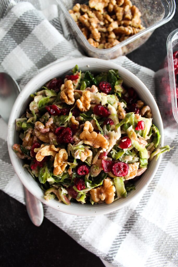 The most delicious Keto Shaved Brussel Sprout Salad made with raw brussels sprouts, dried cranberries, walnuts, and goat cheese in a sweet and tangy vinaigrette.
